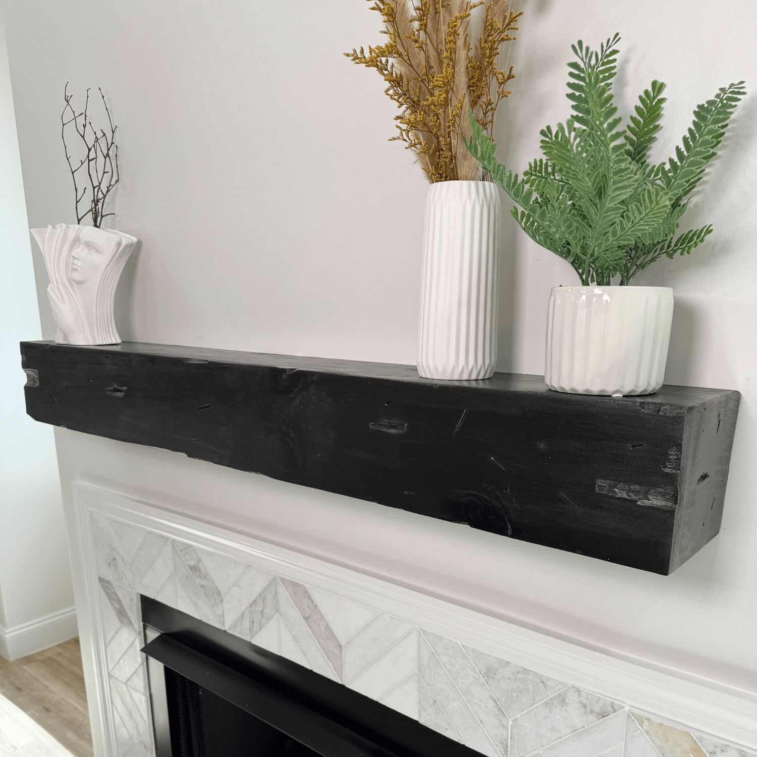 Decorative mantel with white vases and plants against a light gray wall.